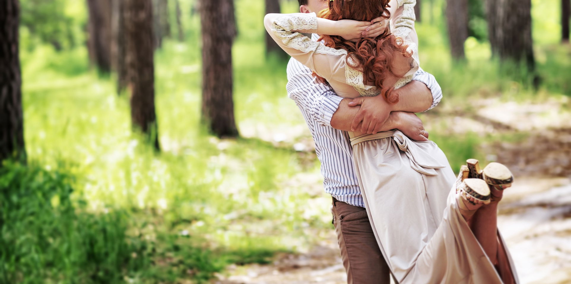 Loving couple having fun in the forest, kissing and whirling around themselves, happy bride and groom enjoying wedding day